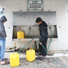 Two boys fill yellow containers with water 