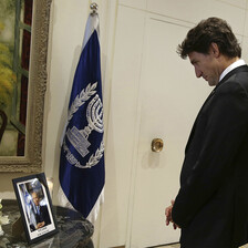 Justin Trudeau looks at a photograph of Shimon Peres next to a bouquet