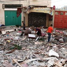 Three boys stand amid rubble