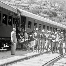 Carriages with people inside and outside and a row of soldiers in helmets