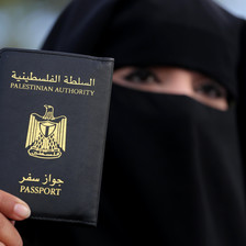 A woman holds up her Palestinian travel document