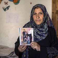 A woman holds a photograph in front of her