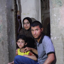 Joud al-Amarin, age 6, who was diagnosed with leukemia, stands near her mother and father.