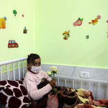 A child in a face mask lies on a hospital bed at the Rantisi Hospital in Gaza.