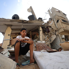 A child sits atop the rubble of a destroyed building in Gaza