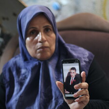 A Palestinian mother holds up a photograph on a phone of her son who died by suicide.