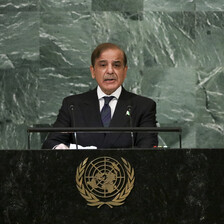 Man stands at a podium with a backdrop of green stone behind him