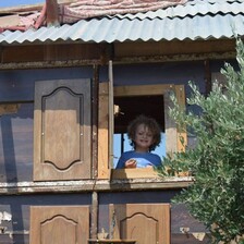 A child looks out the window of a small dwelling