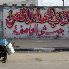 A Palestinian man in Gaza traveling down the street in a wheelchair