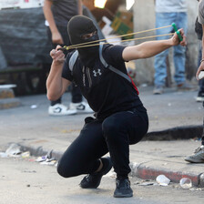 A masked man aims a slingshot