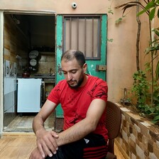 A man sits with his hands resting on his knee