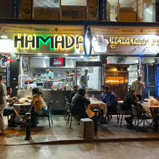 People sit at tables on sidewalk in front of diner at night