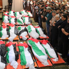 A funeral scene, with a large number of corpses wrapped in flags 