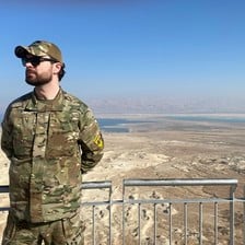 A man in military uniform overlooks a desert