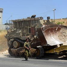 Armed soldiers beside a large bulldozer 