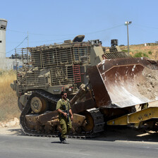 Armed soldiers beside a large bulldozer