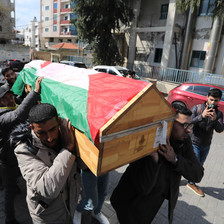 A group of men carry a coffin covered with a flag 