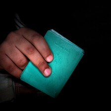 An up-close image of a hand holding a green Palestinian ID document