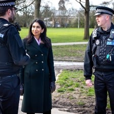 Britain's Home Secretary Suella Braverman chats with two uniformed police officers