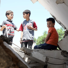 Children play in the rubble of a destroyed house.