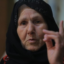 An elderly woman gesticulates with her finger