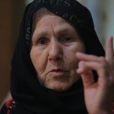 An elderly woman gesticulates with her finger