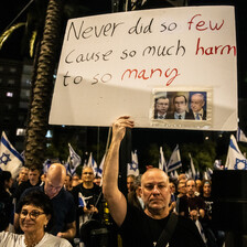 Demonstrators hold up a placard excoriating Israel's leaders for doing "so much harm to so many."