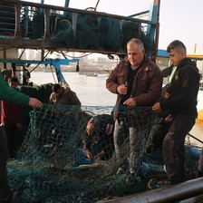 Three men handle a fishing net 