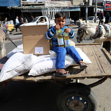 A boy sits on a cart loaded with UN food sacks