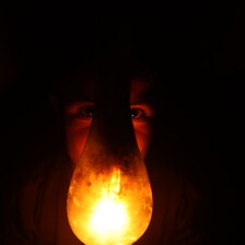 A lamp covers the face of a child amid a general scene of darkness 