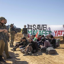 Soldiers surround a group of activists sat on the ground