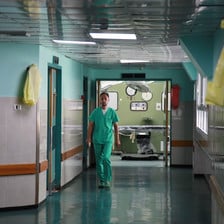 An employee of al-Shifa hospital in Gaza wearing green scrubs walks down a hospital corridor.