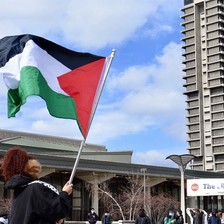 A person holds a Palestinian flag in the courtyard of University of Illinois Chicago.