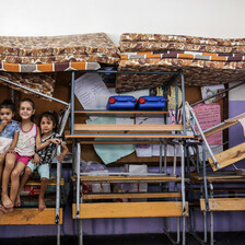 Children sit on stacked up furniture and mattresses