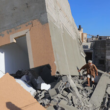 A Palestinian man walks atop rubble of a building destroyed by an Israeli airstrike