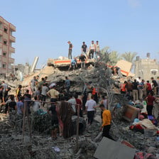 People stand on and beside what remains of a building bombed during Israel's war on Gaza 