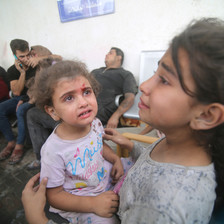 A crying toddler and a young girls wait for medical attention