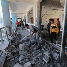 Men and children sift through rubble on the third floor of a damaged building