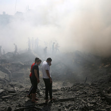 People shrouded in smoke walk through rubble