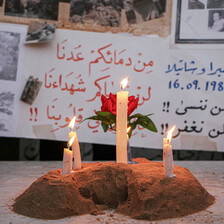 Three lit candles stand before posters remembering the massacres of Palestinian in Lebanon during Israel's invasion which started in 1978