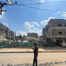 A man stands beside a building in Gaza that has been destroyed by Israel 