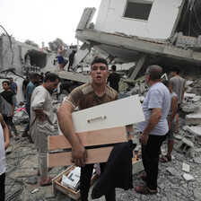 A group of boys and young men searches in what remains of a home bombed by Israel 