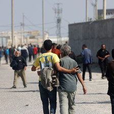 A view of the backs of two men walking, arms around each others' backs