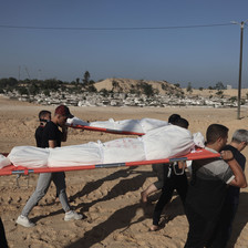 A group of men carry two dead bodies wrapped in shrouds on stretchers following an Israeli airstrike in Gaza 