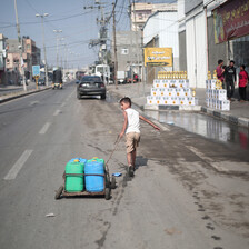 A boy pulls containers on a street in the city of Rafah in the Gaza Strip