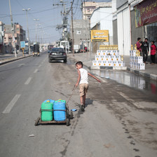 A boy pulls containers on a street in the city of Rafah in the Gaza Strip 