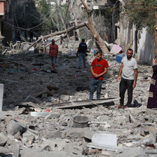 Two men walk down a street that is covered in gray rubble and debris
