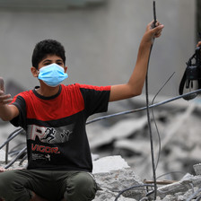 A boy wearing a face mask amid the rubble of a destroyed building in Gaza 
