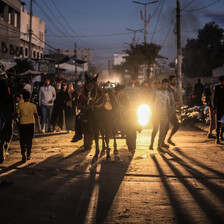 A horse and cart are backlit by car headlights in a street in Gaza