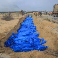A row of blue bags containing corpses in a shallow grave